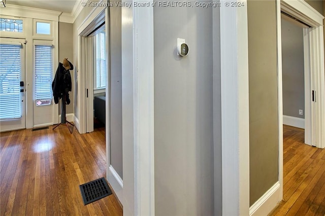 hall with visible vents, baseboards, hardwood / wood-style floors, and crown molding