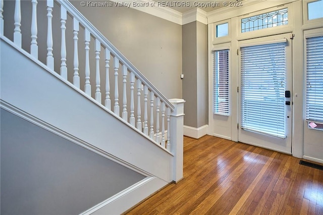 foyer entrance with hardwood / wood-style floors, baseboards, visible vents, ornamental molding, and stairs