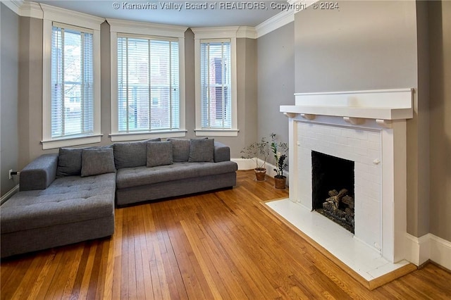 living area with hardwood / wood-style floors, crown molding, a healthy amount of sunlight, and a fireplace