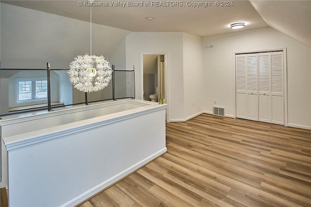 interior space featuring visible vents, baseboards, wood finished floors, and vaulted ceiling