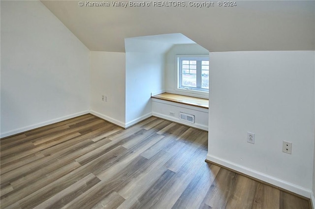 additional living space featuring vaulted ceiling, visible vents, baseboards, and wood finished floors