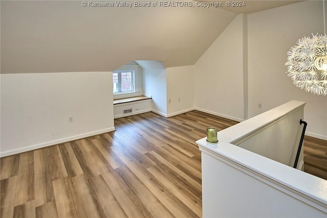 additional living space with lofted ceiling, baseboards, visible vents, and light wood finished floors