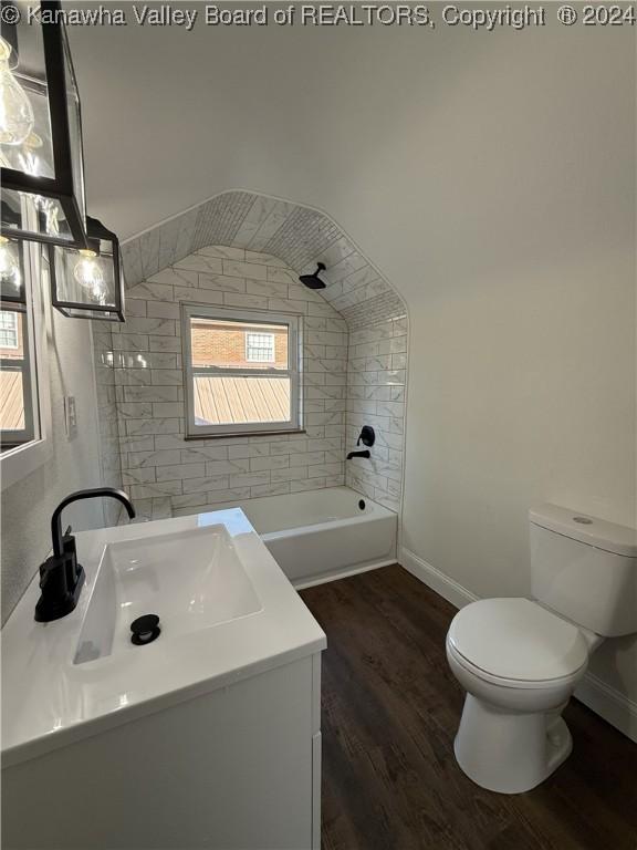 full bathroom featuring hardwood / wood-style flooring, vanity, toilet, and tiled shower / bath combo