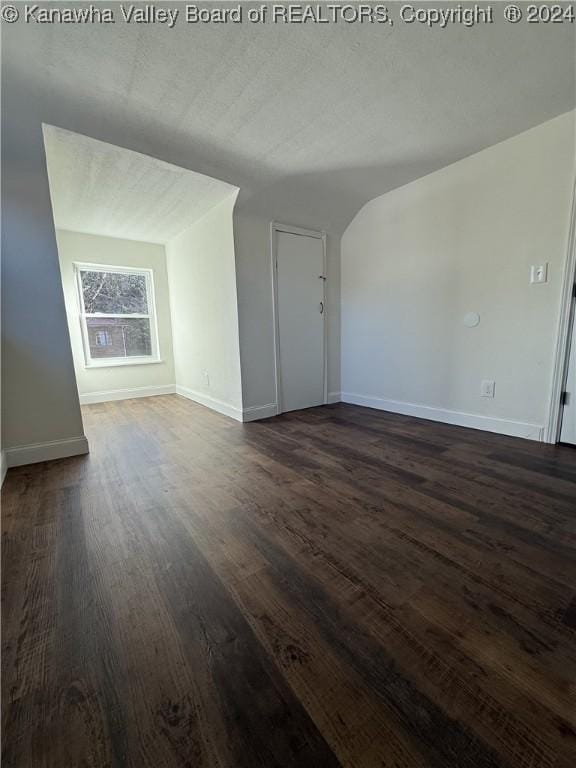 unfurnished living room with a textured ceiling and dark hardwood / wood-style floors