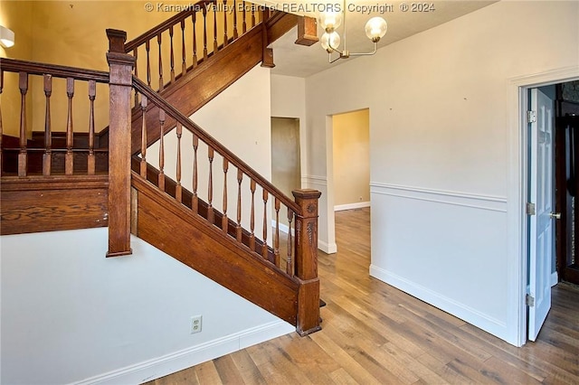 staircase featuring wood-type flooring and a notable chandelier