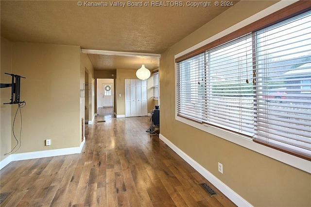 hall with wood-type flooring and a textured ceiling