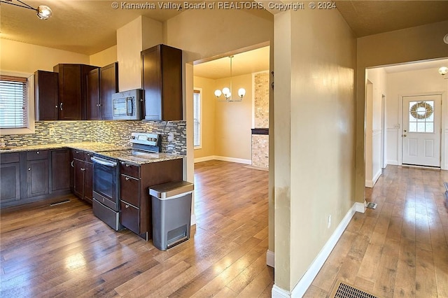 kitchen featuring light stone countertops, appliances with stainless steel finishes, tasteful backsplash, decorative light fixtures, and a notable chandelier