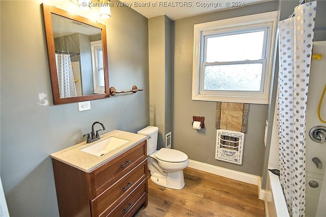 bathroom with wood-type flooring, vanity, heating unit, and toilet