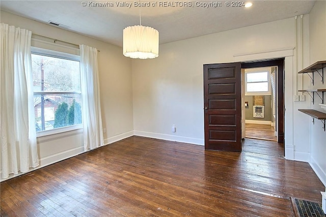 unfurnished dining area featuring heating unit and dark wood-type flooring