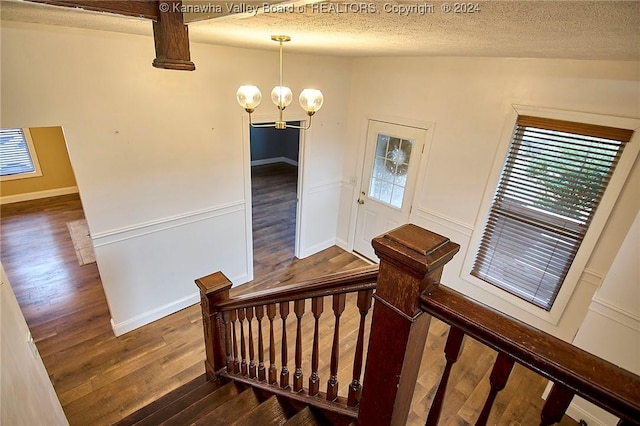 stairway featuring a chandelier, a textured ceiling, and hardwood / wood-style flooring