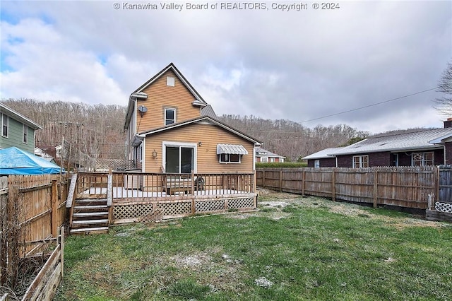 rear view of house featuring a lawn and a wooden deck