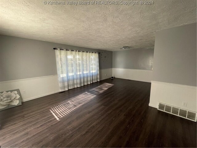 unfurnished room featuring dark wood-type flooring and a textured ceiling