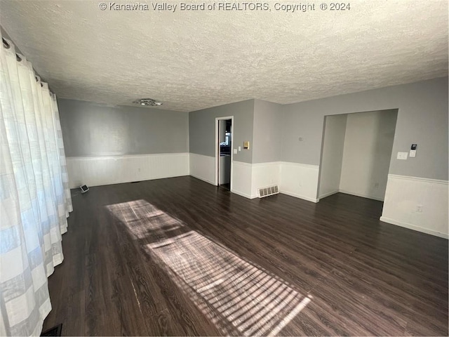 spare room featuring dark hardwood / wood-style floors and a textured ceiling