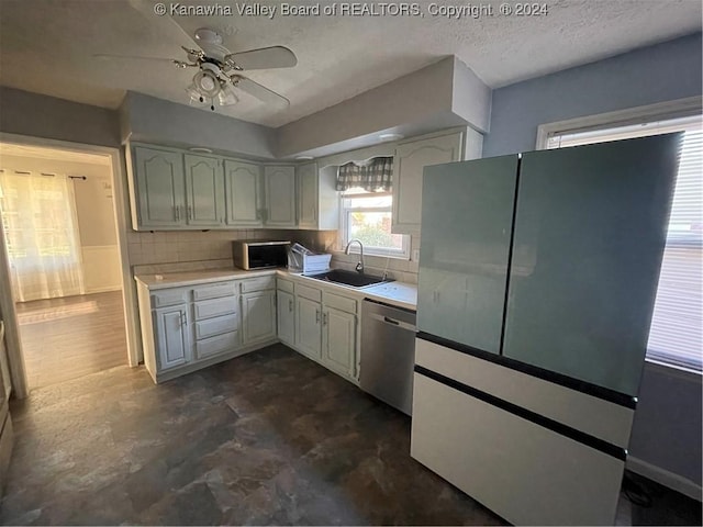 kitchen with ceiling fan, dishwasher, sink, backsplash, and a textured ceiling