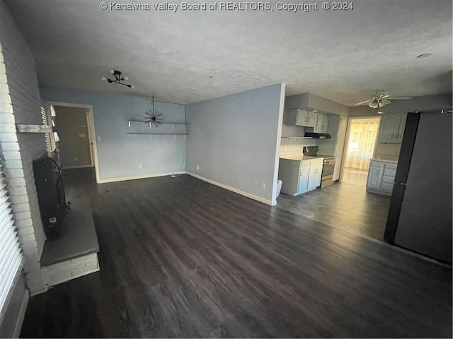 unfurnished living room with dark hardwood / wood-style floors, ceiling fan, a textured ceiling, and a brick fireplace