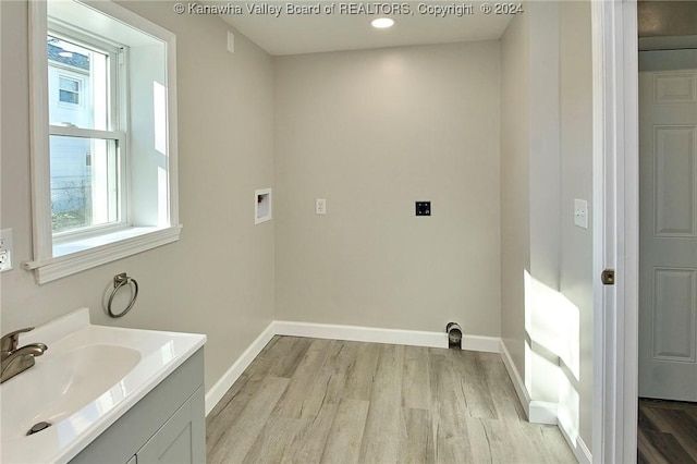 laundry room featuring electric dryer hookup, hookup for a washing machine, light hardwood / wood-style flooring, and sink