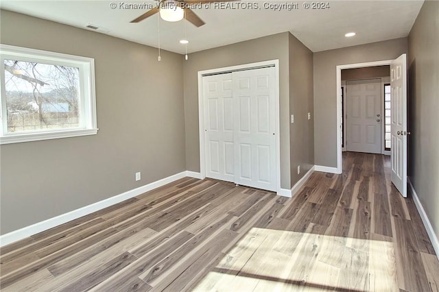 unfurnished bedroom with hardwood / wood-style floors, ceiling fan, and a closet