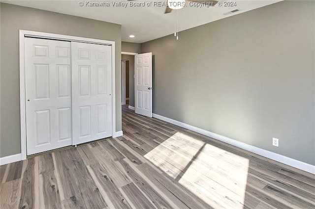 unfurnished bedroom with hardwood / wood-style flooring, ceiling fan, and a closet