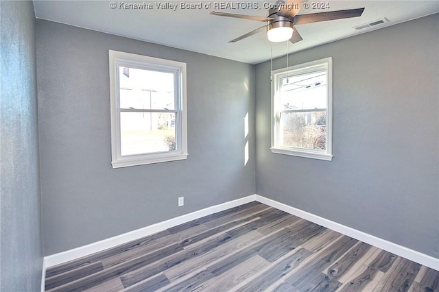 unfurnished room featuring a wealth of natural light, ceiling fan, and dark wood-type flooring