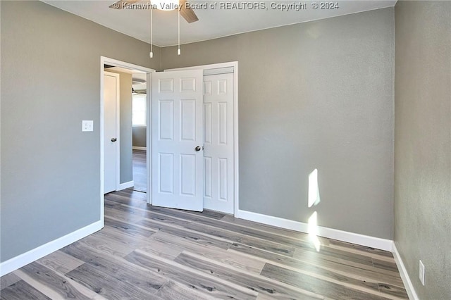 unfurnished bedroom with ceiling fan, a closet, and light wood-type flooring