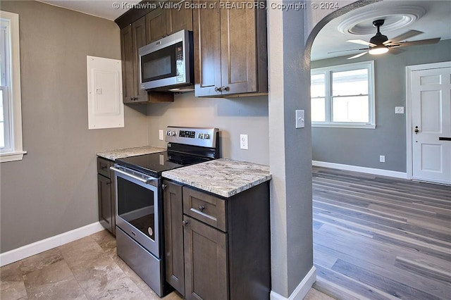 kitchen featuring ceiling fan, stainless steel appliances, light stone counters, electric panel, and dark brown cabinets