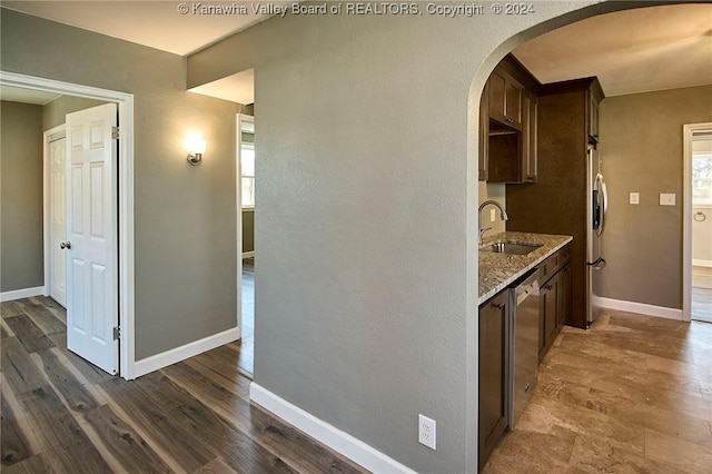 kitchen featuring light stone counters, dark brown cabinetry, sink, and stainless steel appliances