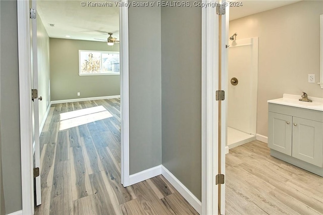 bathroom with a shower, ceiling fan, vanity, and wood-type flooring