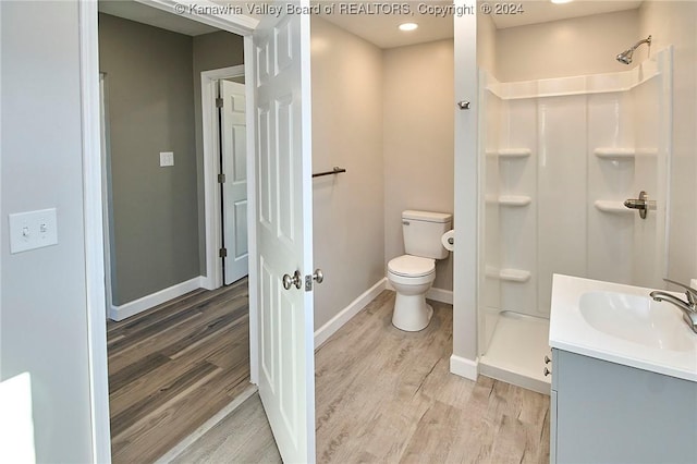 bathroom featuring vanity, hardwood / wood-style flooring, toilet, and walk in shower