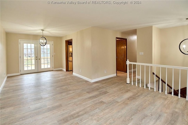 unfurnished room featuring a chandelier, french doors, and light hardwood / wood-style floors