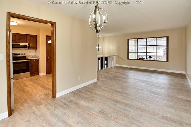 unfurnished living room featuring an inviting chandelier and light hardwood / wood-style flooring