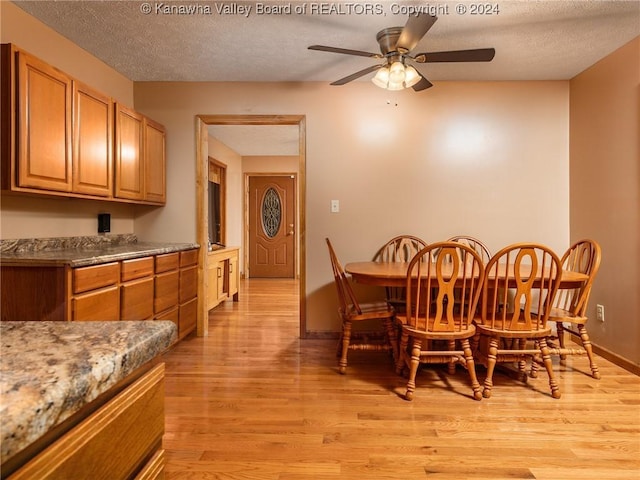 dining area featuring a textured ceiling, light hardwood / wood-style flooring, and ceiling fan