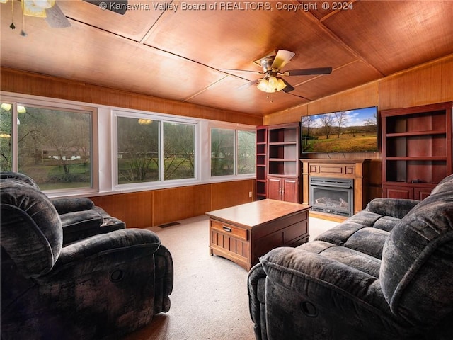 carpeted living room featuring wooden walls, ceiling fan, and wooden ceiling