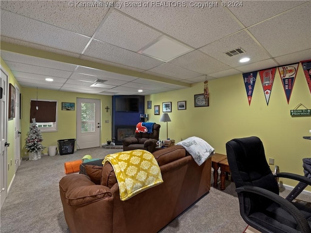 carpeted living room featuring a paneled ceiling and a large fireplace