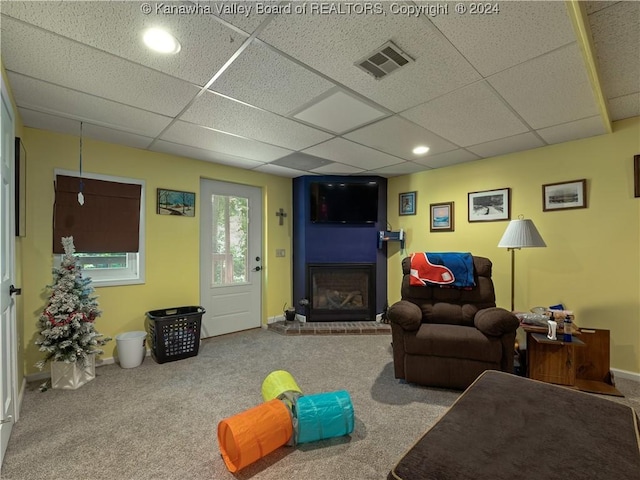 carpeted living room featuring a drop ceiling