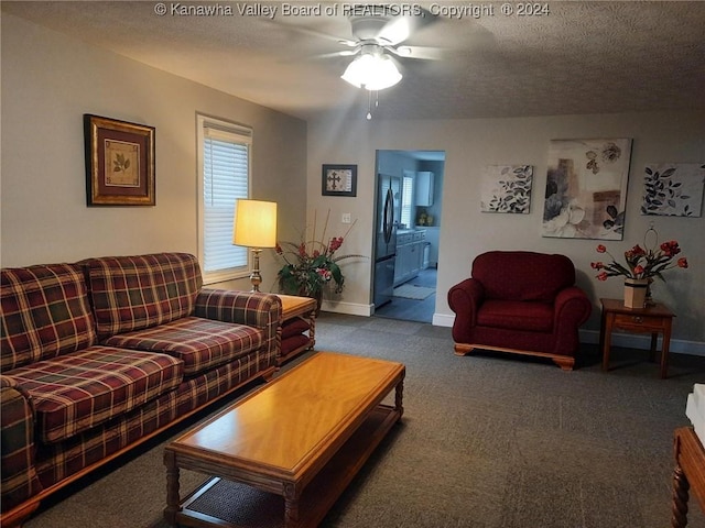 carpeted living room featuring ceiling fan and a textured ceiling