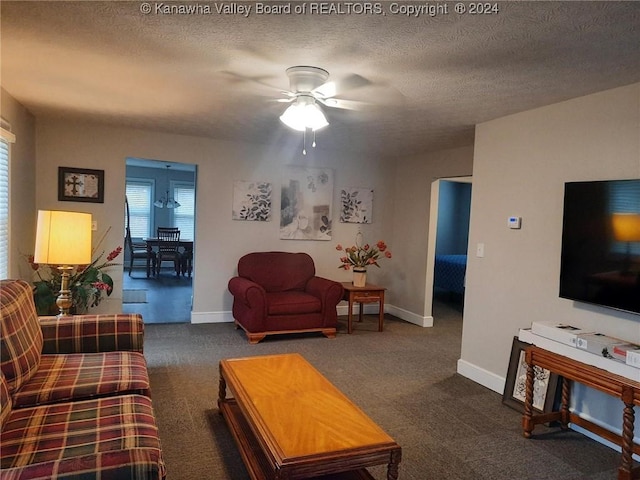 living room with a textured ceiling, dark carpet, and ceiling fan