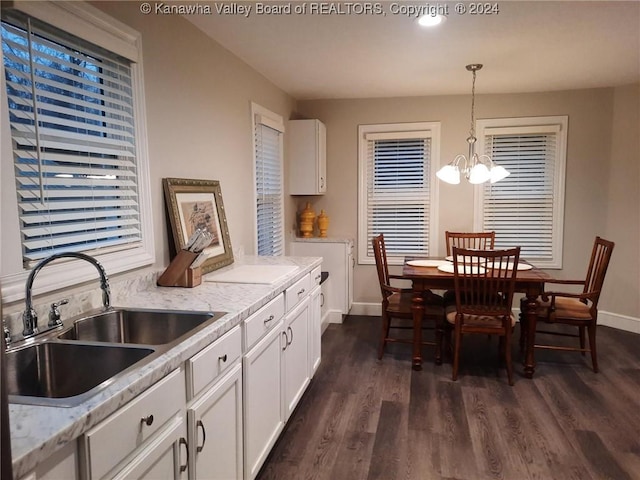 kitchen with dark wood-type flooring, white cabinets, sink, decorative light fixtures, and a chandelier