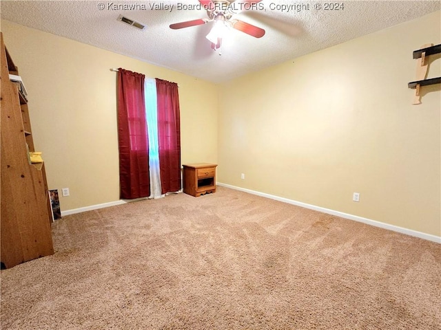 spare room with a textured ceiling, carpet floors, and ceiling fan