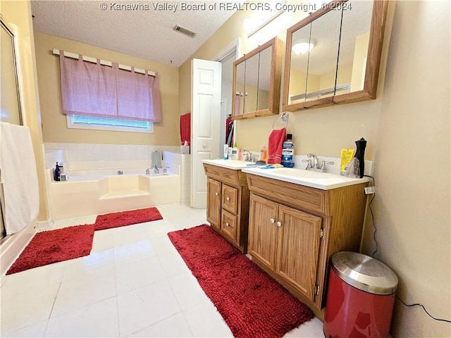 bathroom with tile patterned floors, a washtub, vanity, and a textured ceiling