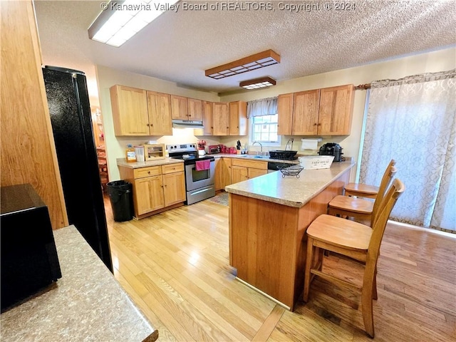 kitchen with a kitchen breakfast bar, light hardwood / wood-style flooring, kitchen peninsula, a textured ceiling, and electric stove