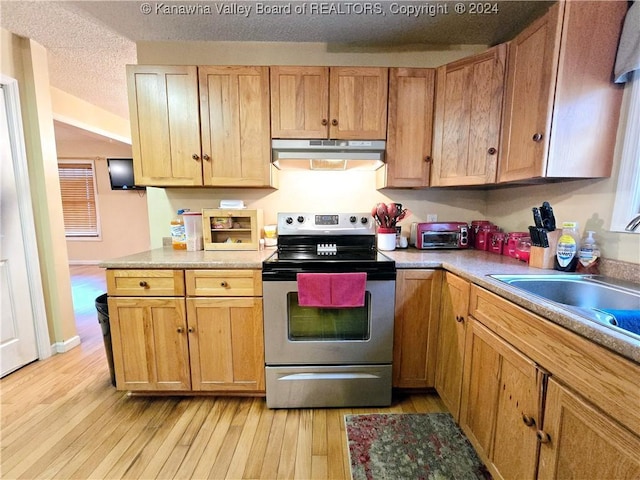 kitchen featuring stainless steel electric range oven, light hardwood / wood-style flooring, a textured ceiling, and sink