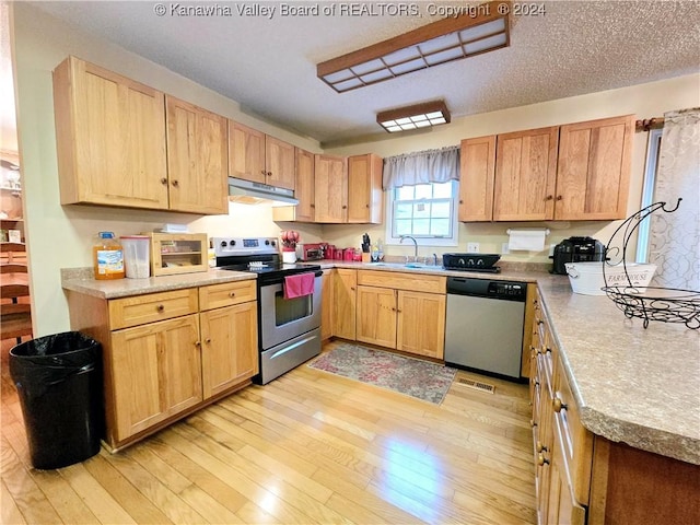 kitchen with sink, light wood-type flooring, a textured ceiling, and appliances with stainless steel finishes