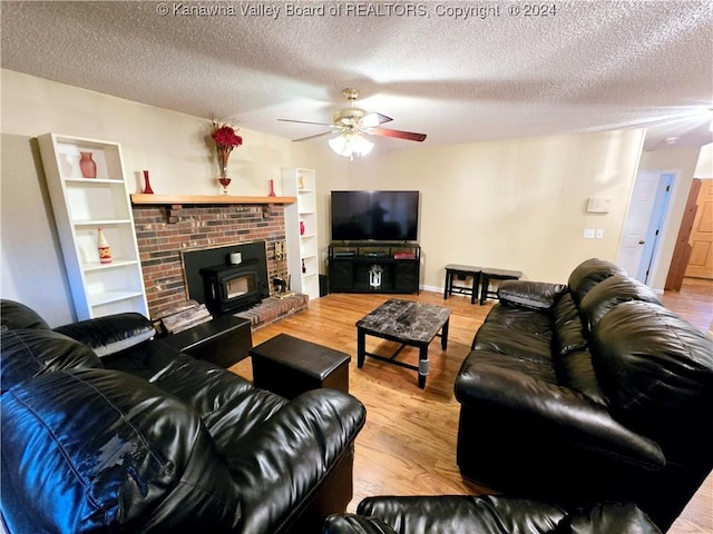 living room featuring a wood stove, ceiling fan, hardwood / wood-style floors, and a textured ceiling