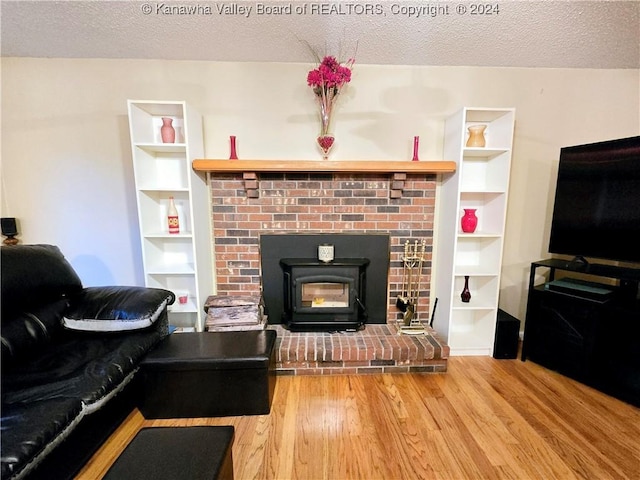 living room with a wood stove, wood-type flooring, and a textured ceiling