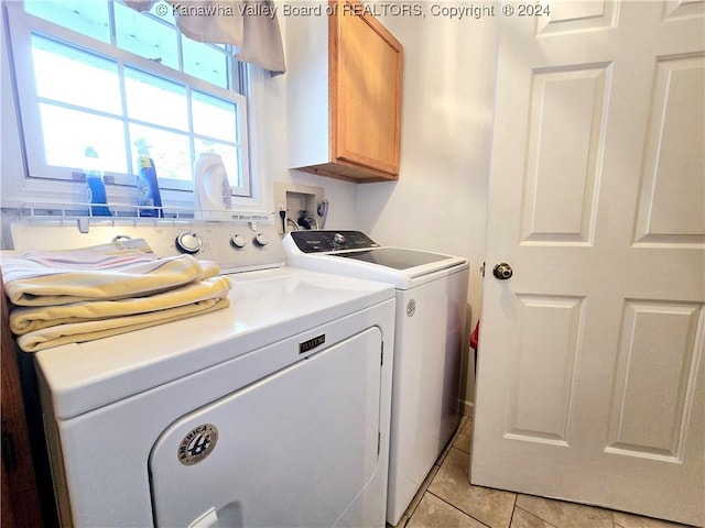 laundry area with light tile patterned flooring, cabinets, and separate washer and dryer