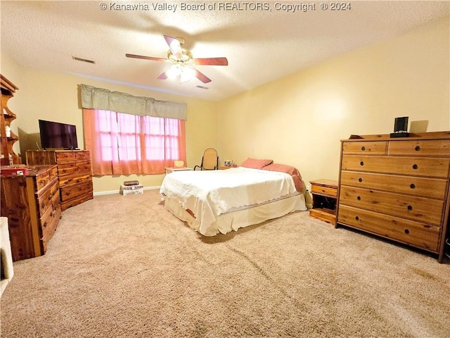 carpeted bedroom featuring ceiling fan and a textured ceiling