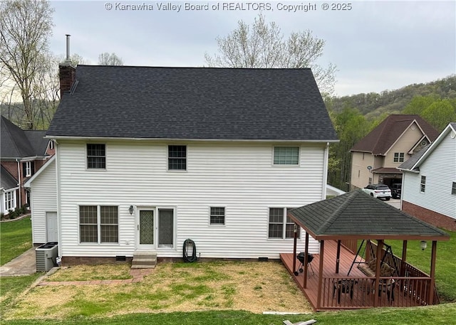 rear view of property with central AC unit, a chimney, a lawn, roof with shingles, and entry steps