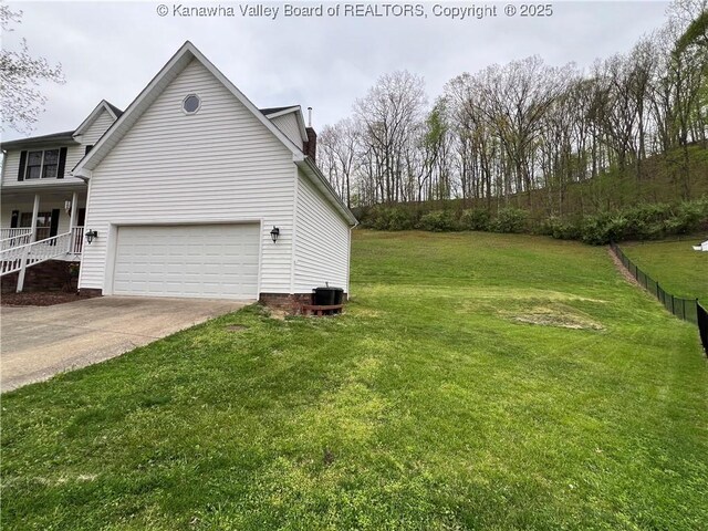 view of side of home featuring a garage, a lawn, central AC unit, and concrete driveway