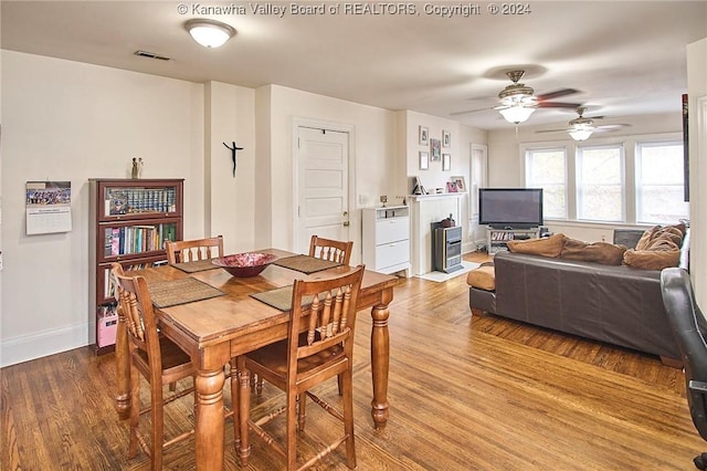 dining room with a ceiling fan, wood finished floors, visible vents, and baseboards