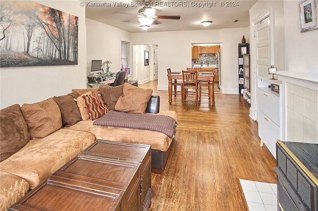 living room featuring baseboards, light wood-style floors, and a ceiling fan